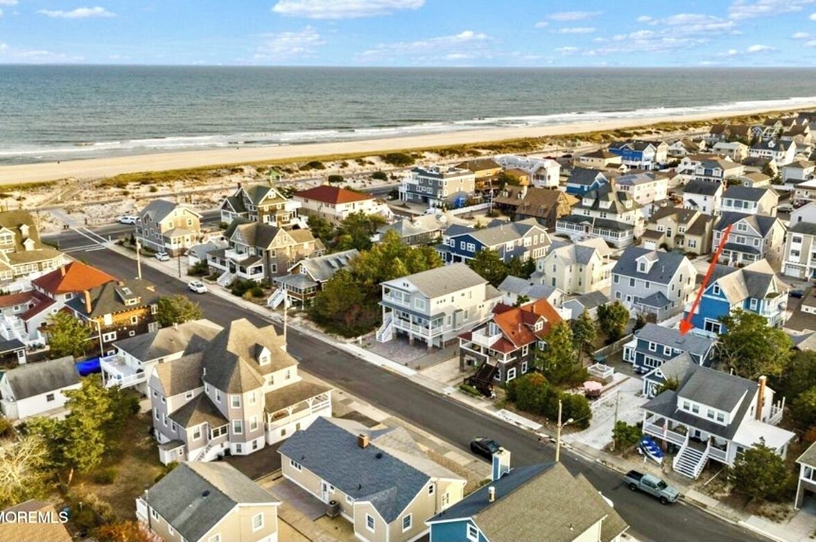 Una zona residenziale costiera con case, spiaggia e cielo sereno.
