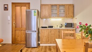 Une cuisine compacte avec des meubles en bois, un réfrigérateur en acier inoxydable, un four à micro-ondes et une table à manger.