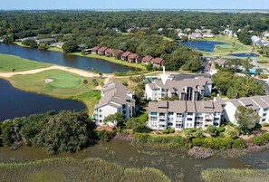 A residential area with multiple buildings, a golf course, and a lake.