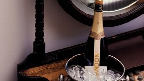 A wooden table with a bottle of champagne in a bucket, two glasses, and a tray with bottles. - Australian Heritage Hotel (The Rocks)