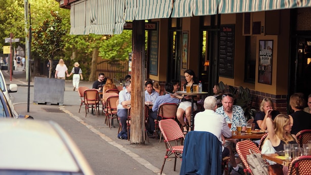 An outdoor cafe with tables and chairs, a striped awning, and a brick building facade. - Australian Heritage Hotel (The Rocks)