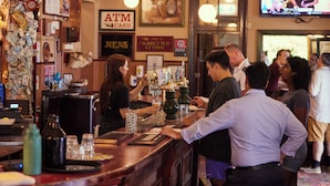 A bar area with a bartender, customers, and a TV screen displaying a basketball game. - Australian Heritage Hotel (The Rocks)