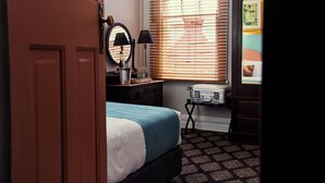 A bedroom with a bed, dresser, mirror, lamp, and a suitcase. - Australian Heritage Hotel (The Rocks)