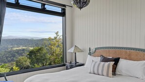 Un dormitorio con un ventanal que ofrece una vista panorámica de un paisaje boscoso.