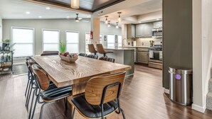 Een ruime keuken met een groot eiland, moderne apparaten en een eethoek met een houten tafel en stoelen.