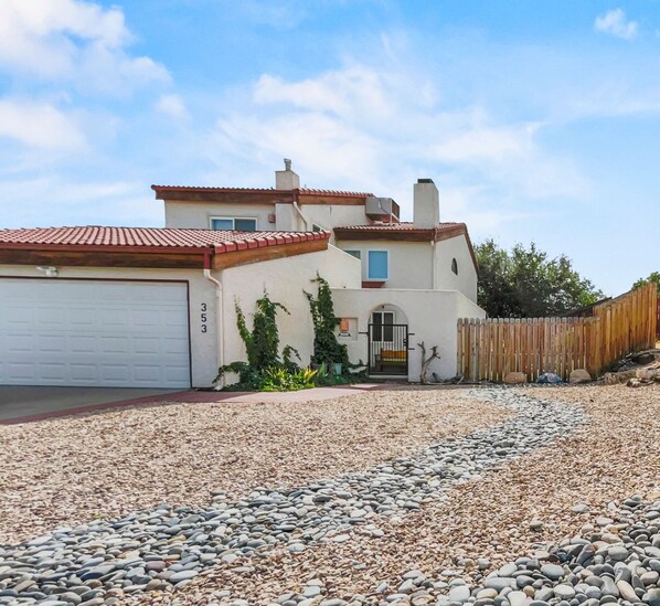 Une maison à deux étages avec un garage, une allée en gravier et une clôture en bois.