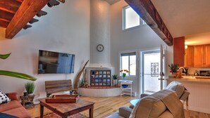 Un salon spacieux avec une cheminée, un grand téléviseur et un coin salon confortable.