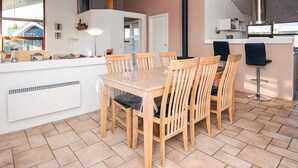 Una cocina moderna con una isla central, sillas de madera, una estufa integrada y un ventanal grande.