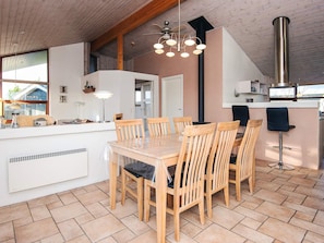 A modern kitchen with a central island, wooden chairs, a built-in stove, and a large window. - 4 Star Holiday Home in Tarm (Tarm)