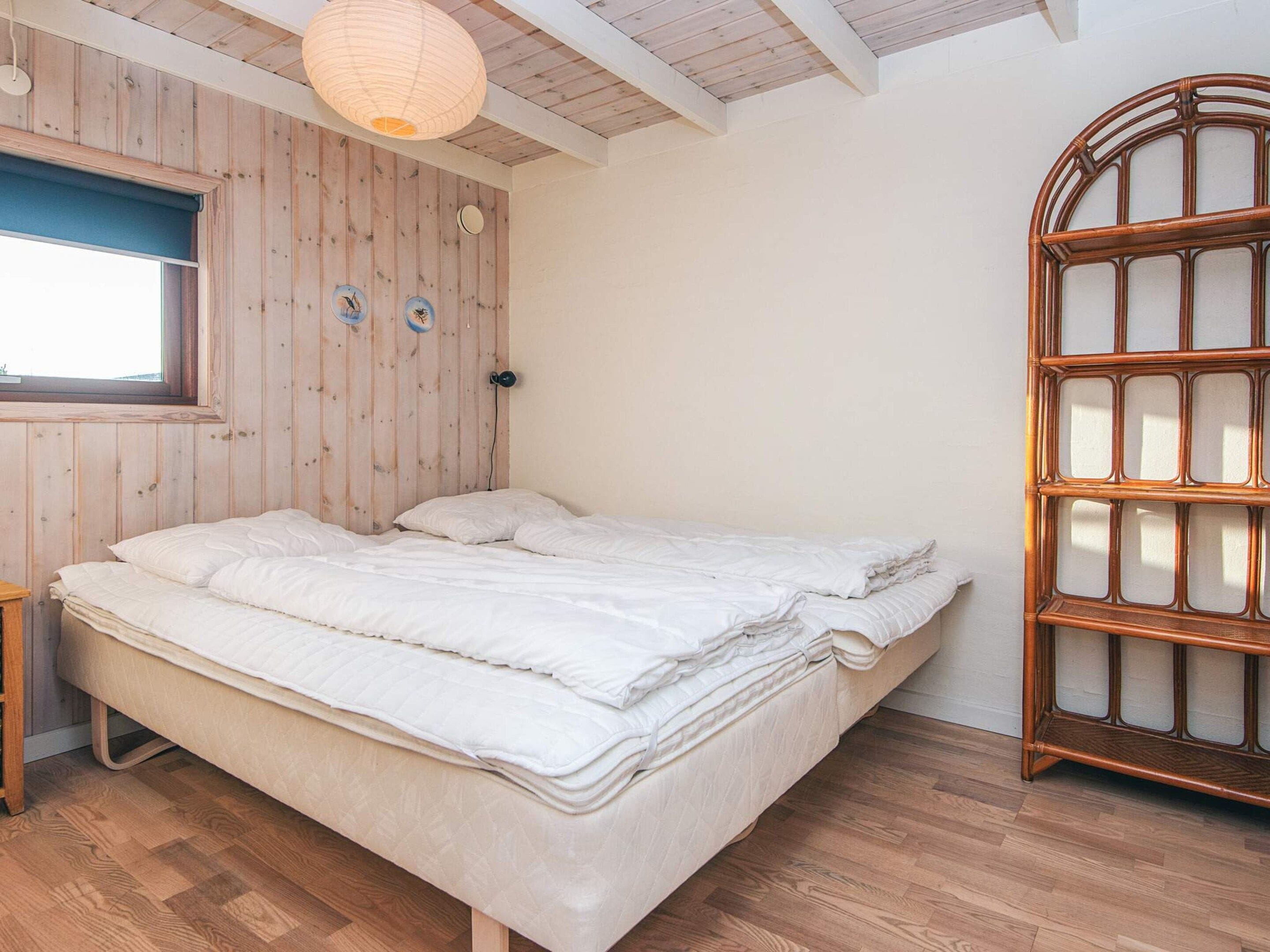 Un dormitorio con cama de madera, una ventana y un estante en la pared.
