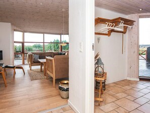 A spacious living area with a wooden ceiling, large windows, a sofa, chairs, a small table, and a TV. - 4 Star Holiday Home in Tarm (Tarm)