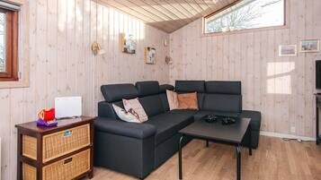 Una sala de estar acogedora con un sofá modular, una mesita de centro y unidades de almacenamiento de mimbre.