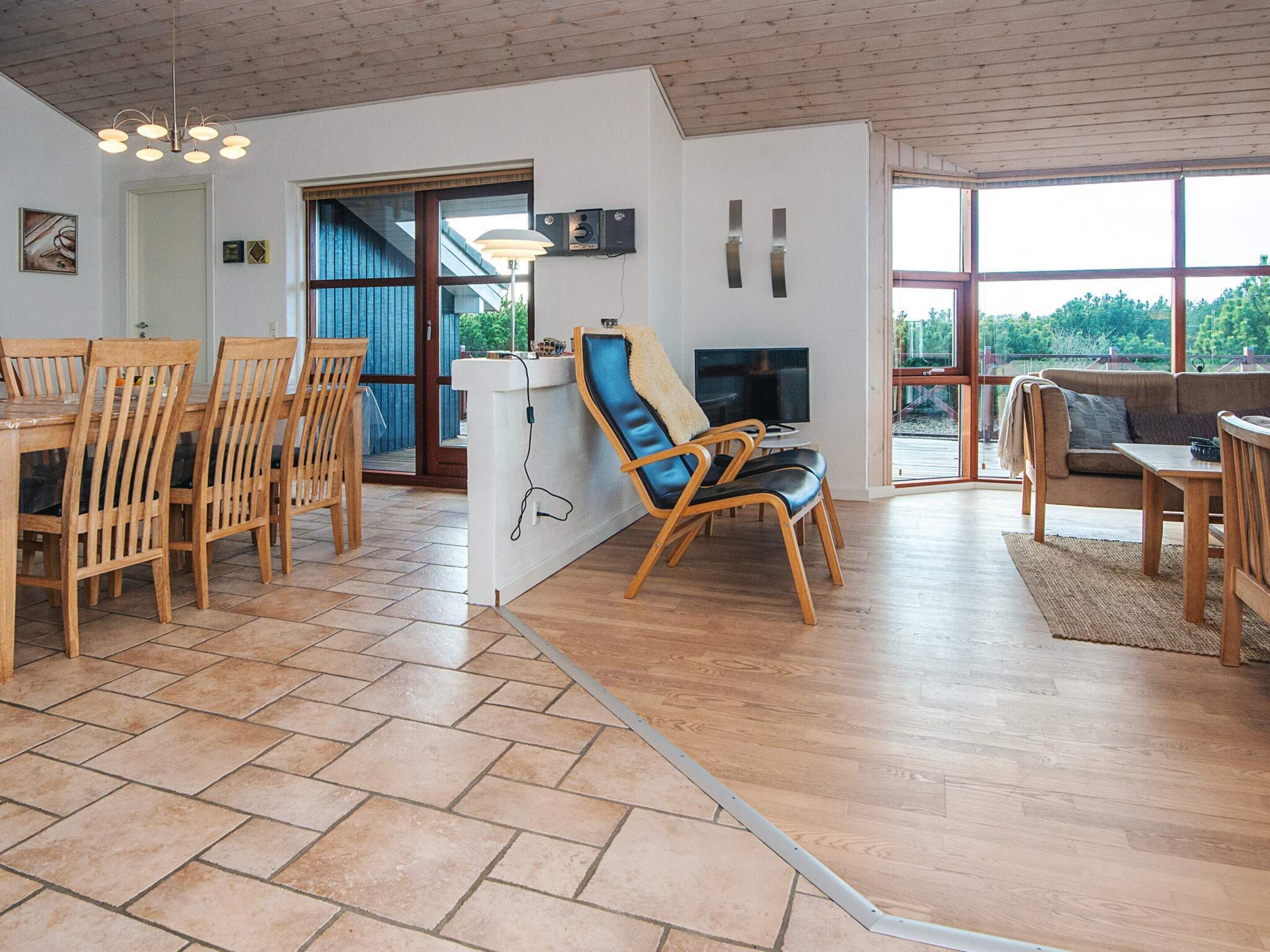 Uma sala ampla com uma mesa de jantar de madeira, cadeiras, sofá e televisão.