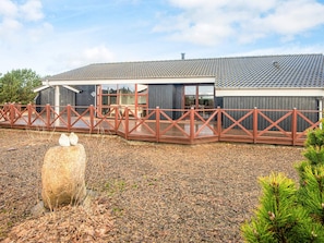 A modern building with a grey roof, a wooden deck, and a fenced area. - 4 Star Holiday Home in Tarm (Tarm)