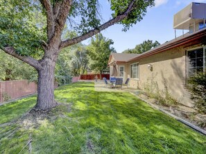 Relax in the serene backyard with a patio area perfect for dining or unwinding under the shade of a large tree.