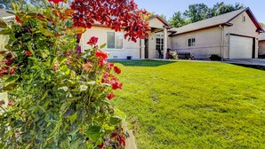 Une propriété résidentielle dotée d’une pelouse bien entretenue, d’une maison avec un garage et d’un jardin agrémenté de fleurs rouges.