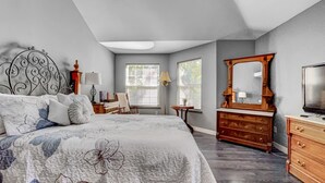 Une chambre à coucher avec un grand lit, une commode en bois, un miroir et un téléviseur.