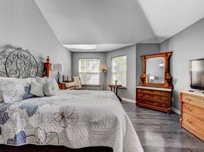 Cozy retreat with a large bed, dresser, TV, and comfortable seating area.