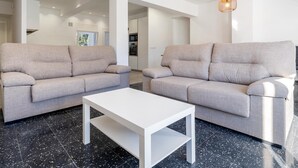 A modern living room with two grey sofas, a white coffee table, and a pendant light. - Space with 5 bedrooms, 3 terraces and 150m beach (Platja d'Aro)