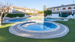 Una piscina de disseny circular, envoltada d'un passeig pavimentat i gespa verda.