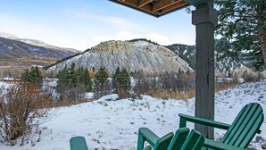 A snow-covered landscape with a wooden structure and green Adirondack chairs. - 100 Ridgepoint 4 Bedroom Condo (Avon)