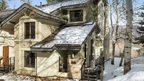 A two-story house with a sloped roof, a front porch, and a stone foundation. - 100 Ridgepoint 4 Bedroom Condo (Avon)