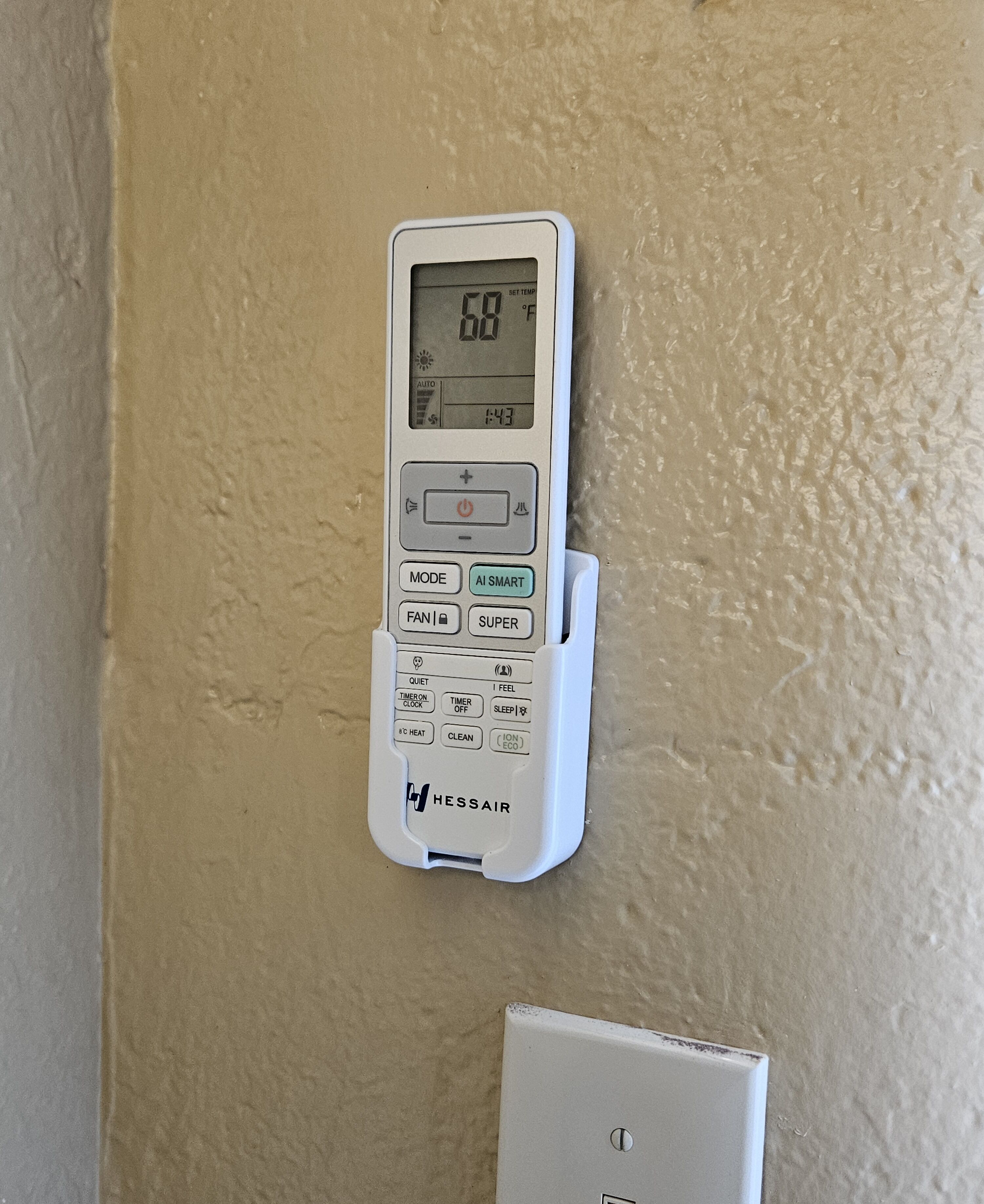 Termostato digital fixado em parede bege texturizada, exibindo uma temperatura de 20°C.