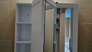 A bathroom vanity with a mirror, three lights, and a shelf.