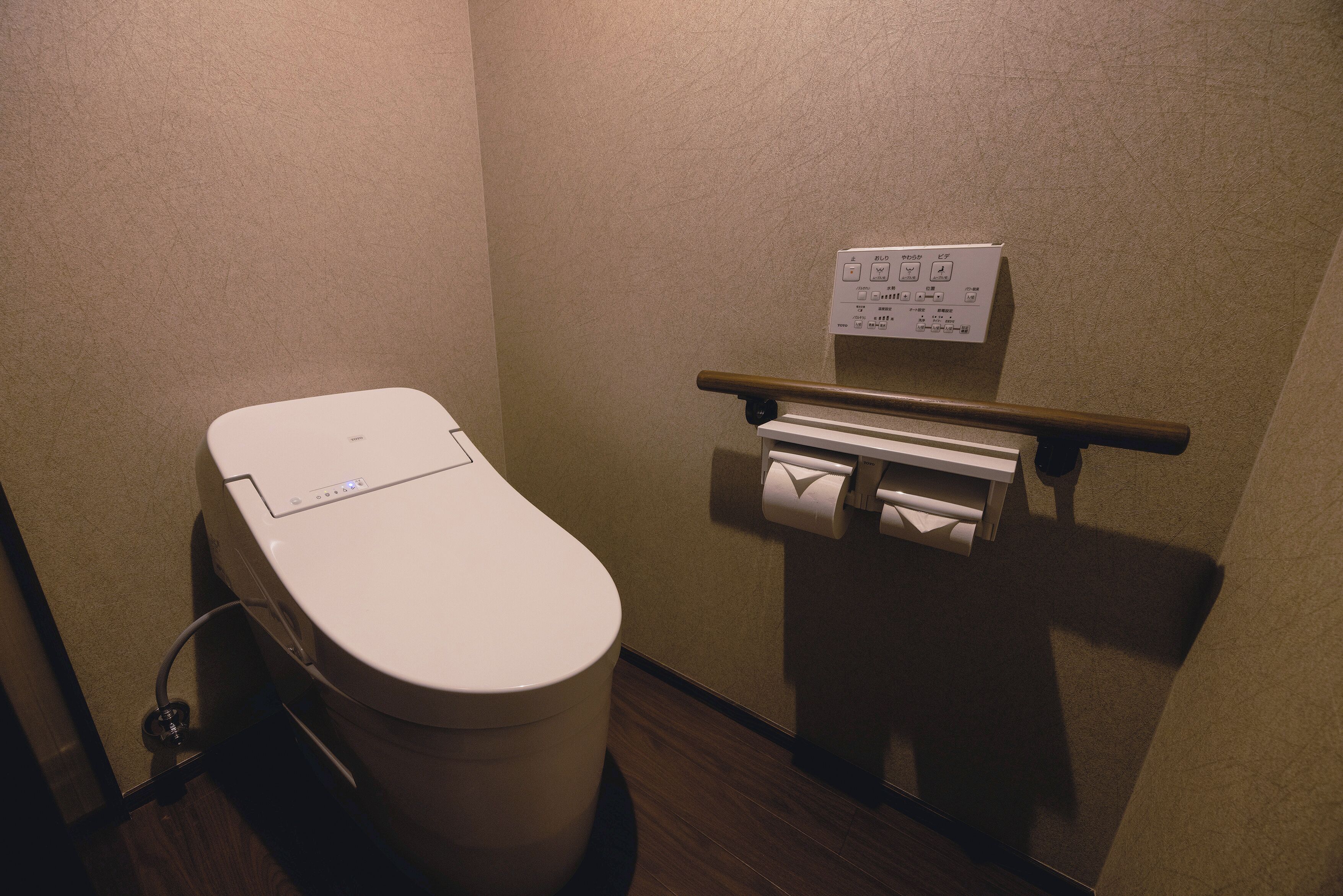 A small, private bathroom with a toilet, a hand dryer, and a paper towel dispenser.