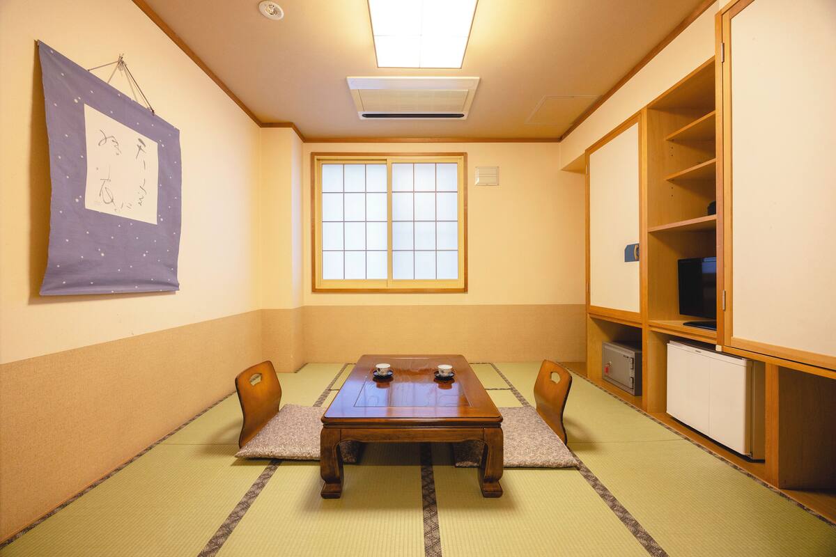 Une pièce de style japonais traditionnel, avec un sol recouvert de tatamis, une petite table en bois et une porte coulissante.