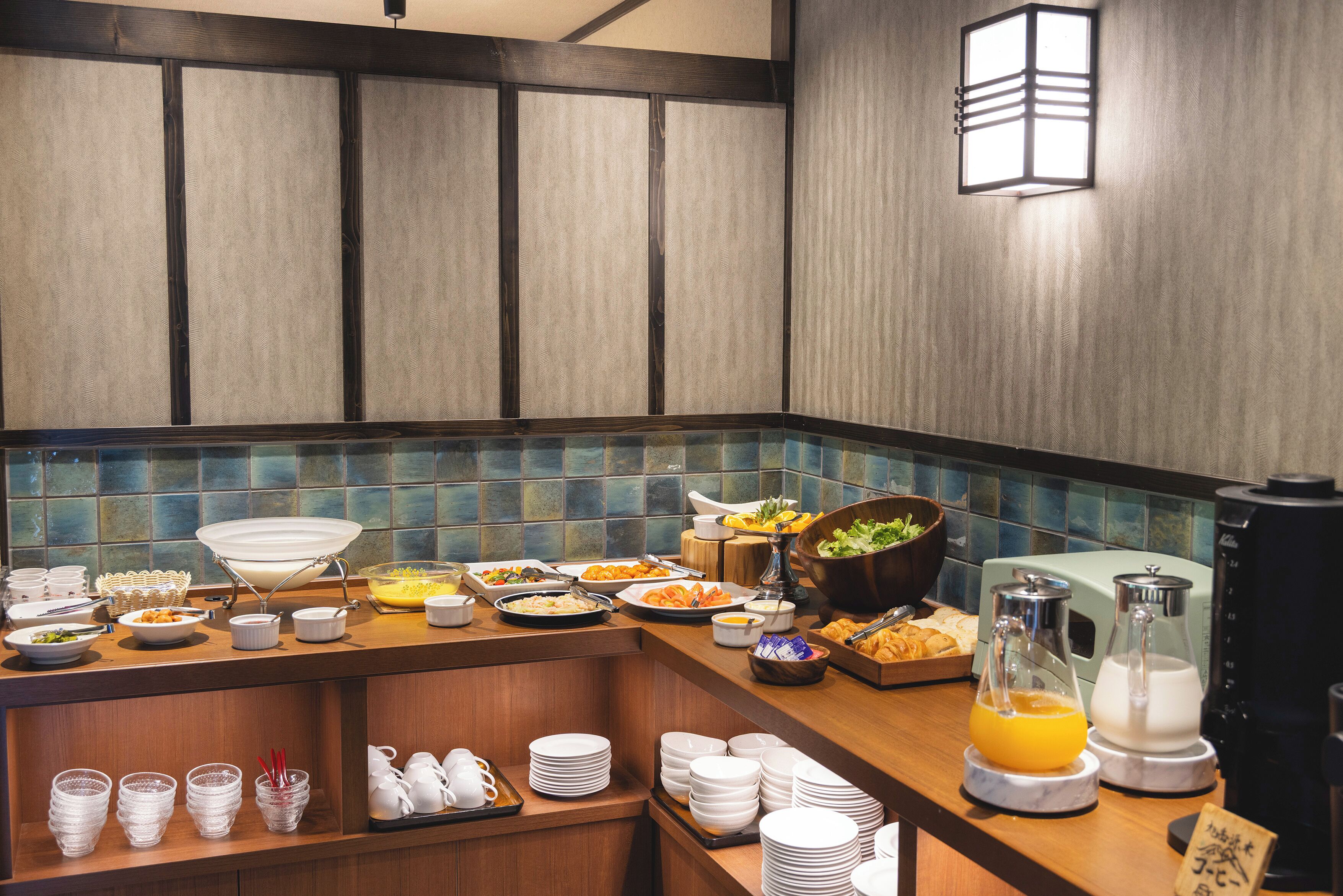 A buffet setup with various food items and beverages, including a coffee maker and a juice dispenser.
