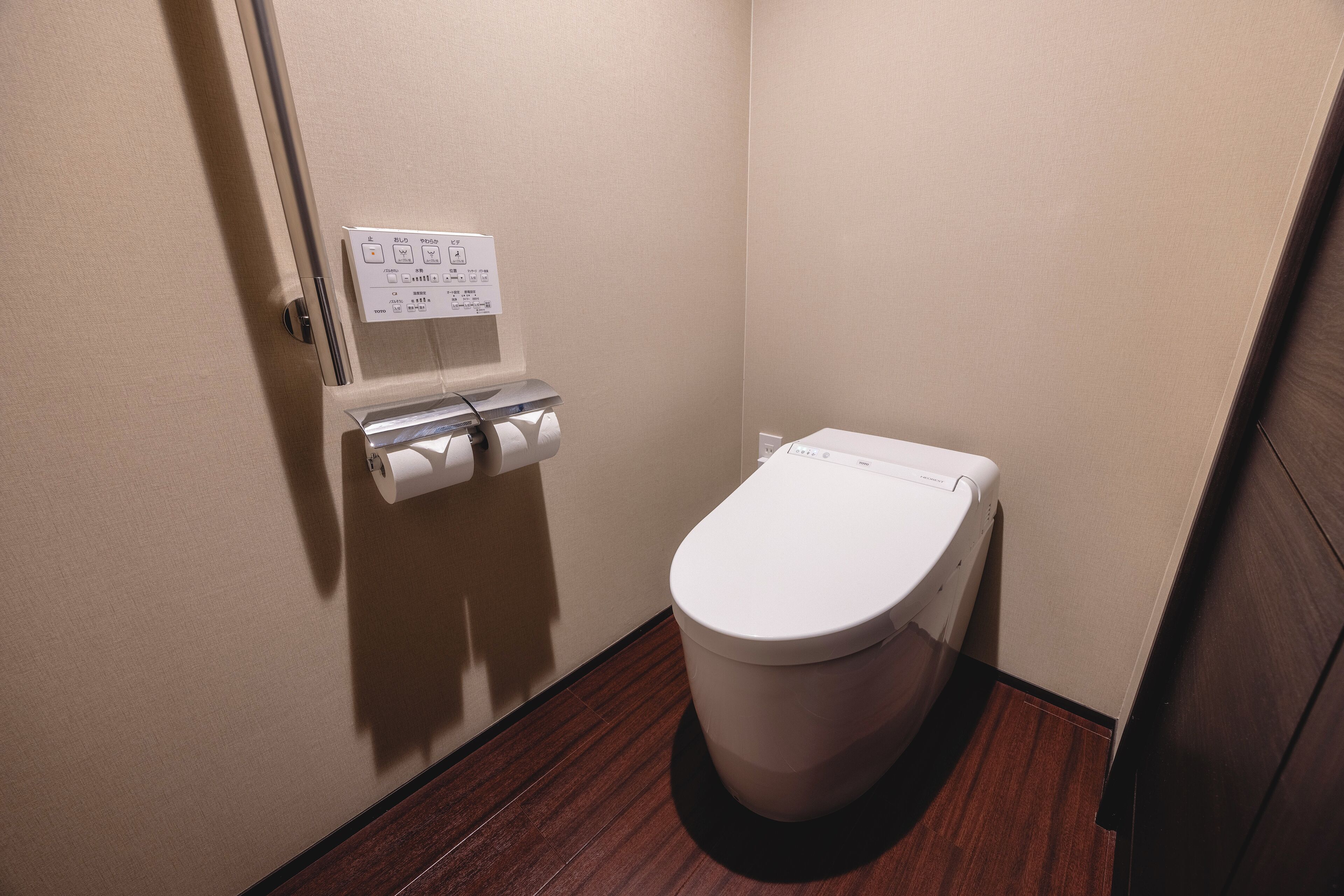 A small, clean bathroom with a toilet, a paper towel dispenser, and a hand dryer.