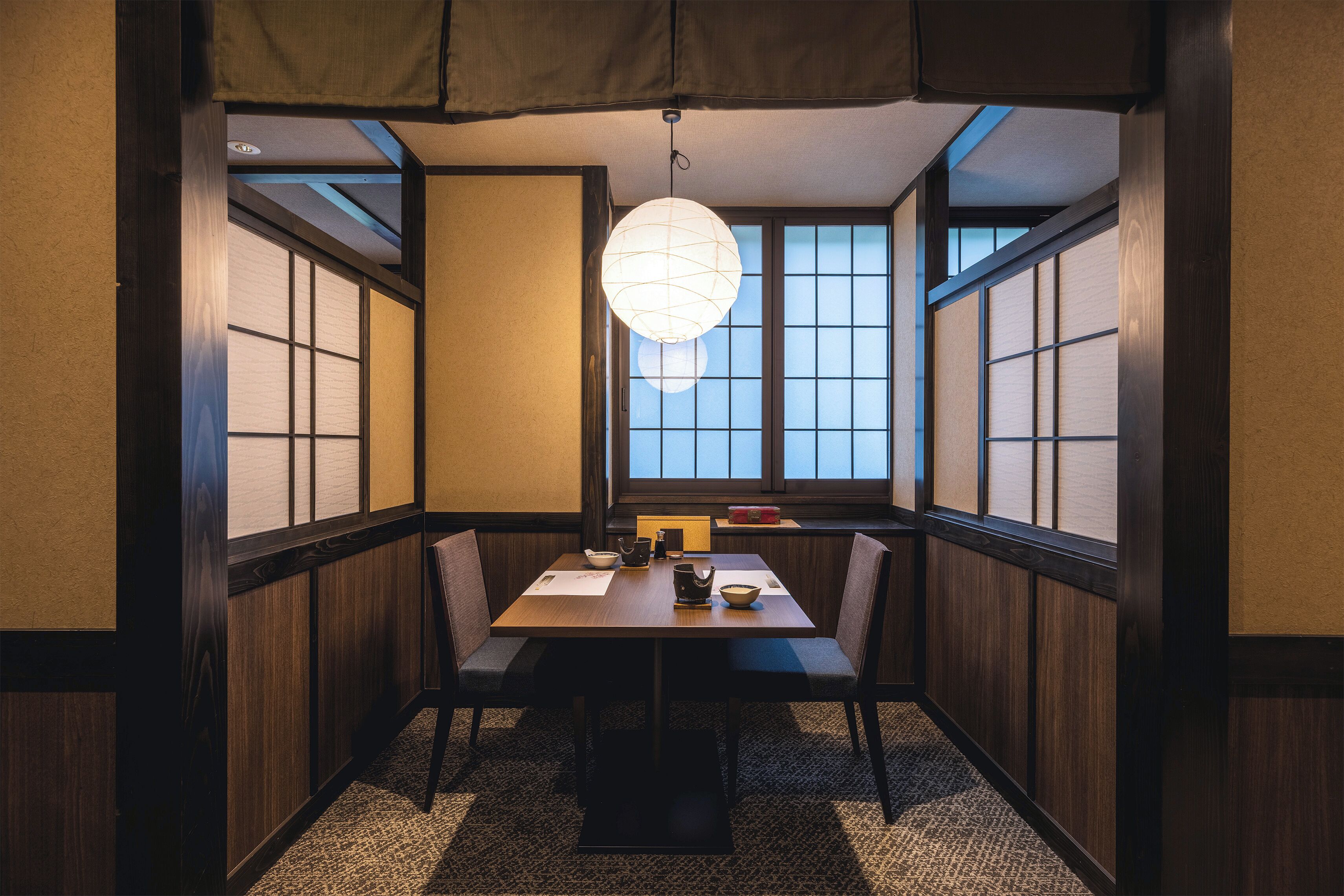 A traditional Japanese dining room with tatami flooring, a low table, and shoji screens.