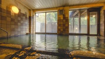 Una piscina techada con calefacción, paredes de azulejos y techo de madera.