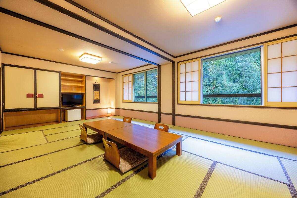 Une pièce de style japonais traditionnel, avec un sol recouvert de tatamis, une table en bois et des portes coulissantes.