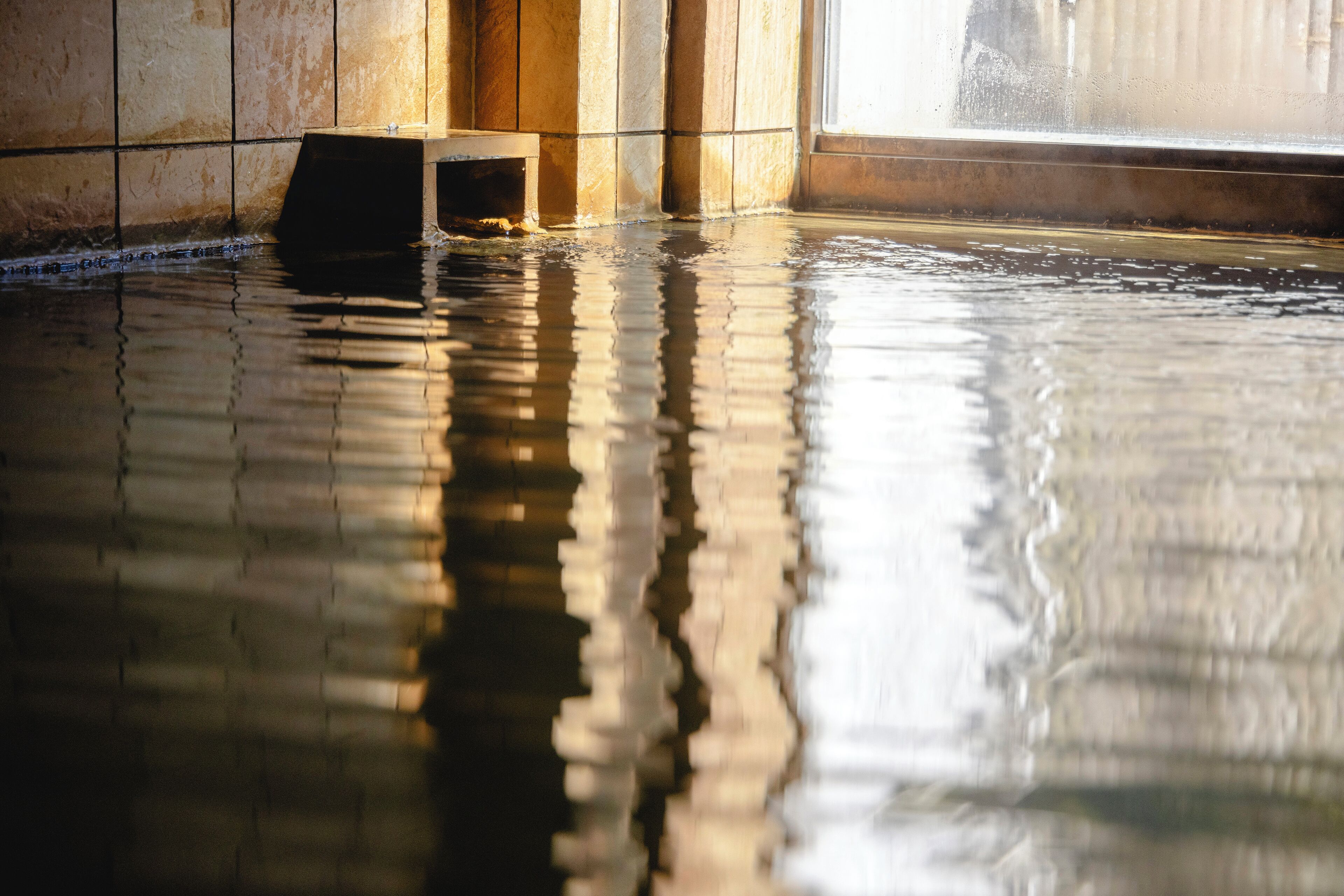 Una habitación inundada, con paredes de azulejos y un banco.