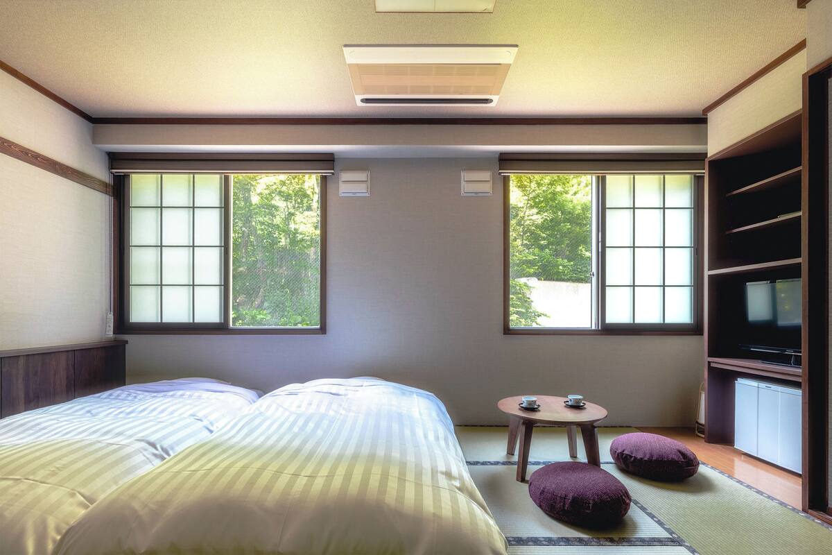 Une chambre d’hôtel avec un lit, une petite table et une tasse, ainsi qu’une télévision.