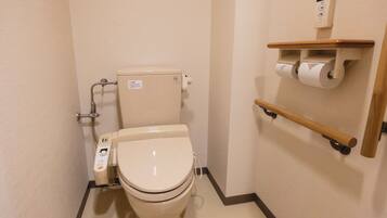 A small, modern bathroom with a toilet, a hand sanitizer dispenser, and a toilet paper holder on a wall-mounted shelf.