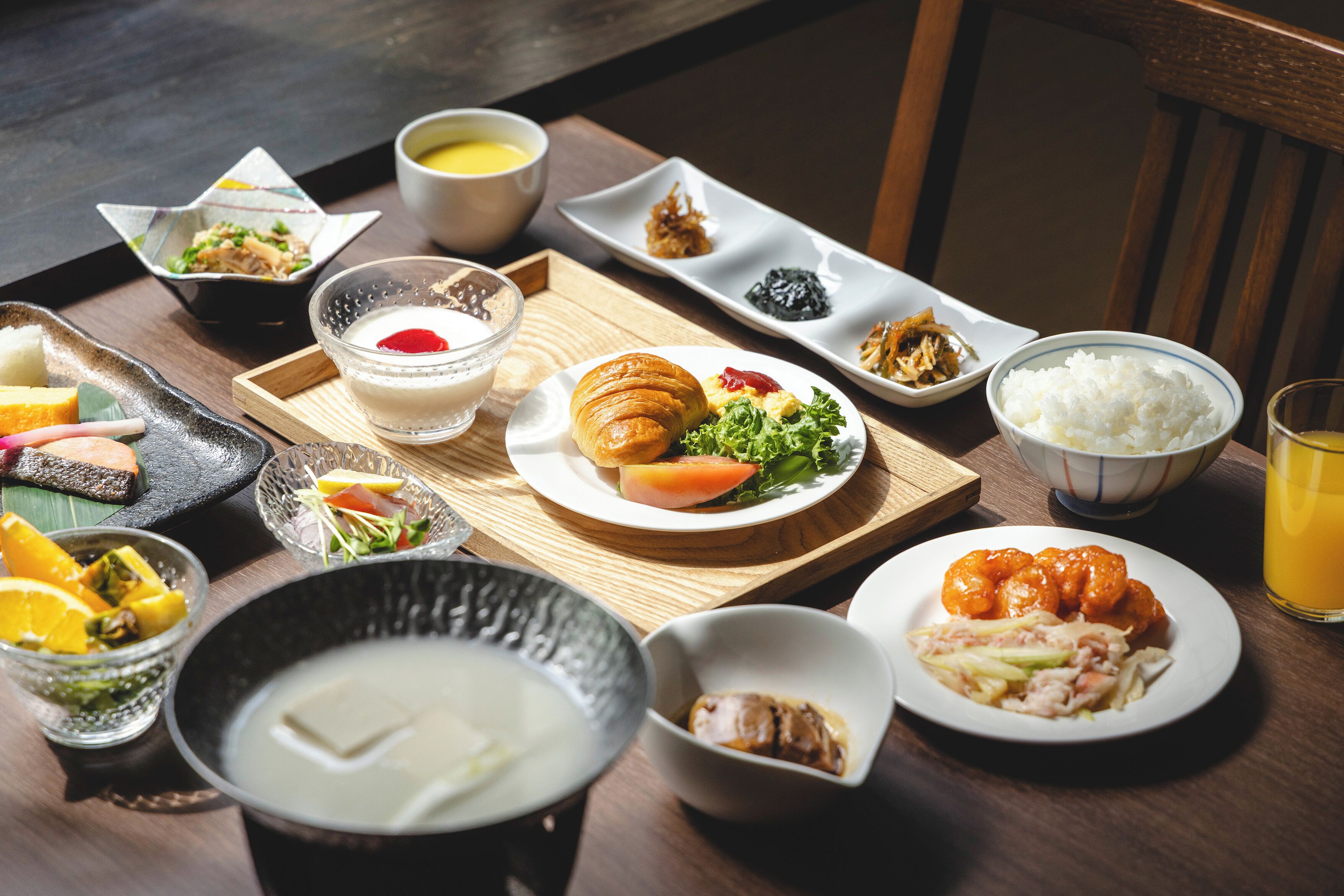 Une variété de plats, dont un croissant, une salade et du riz, disposés sur une table en bois.