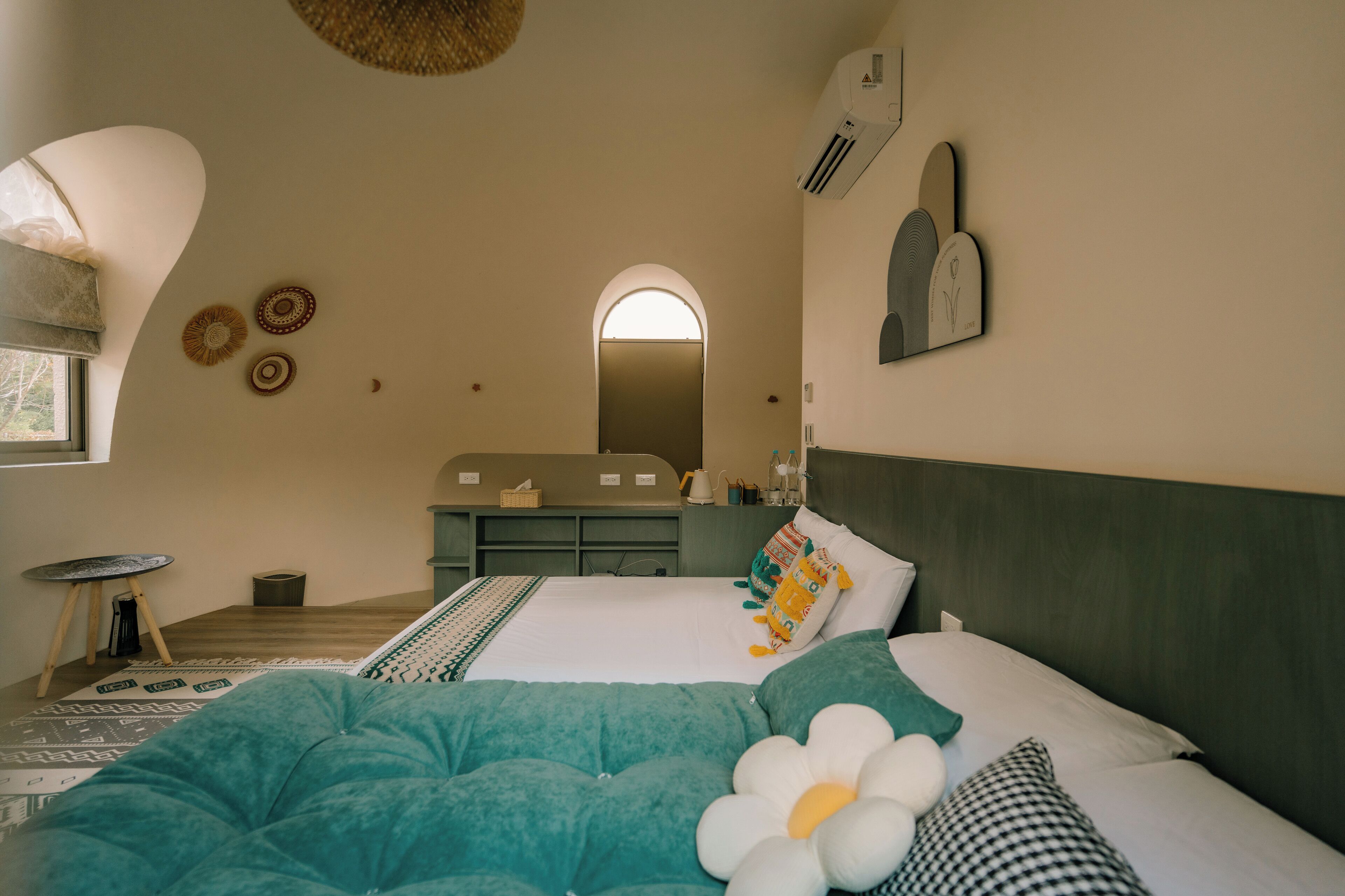 A bedroom with two beds, a vanity with a mirror, and a window with a view.