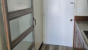Une pièce dotée d’une porte-fenêtre coulissante, d’une porte blanche et d’armoires en bois.