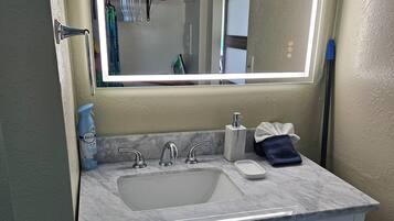 A bathroom with a white sink, a mirror with a light, and a cabinet with drawers.