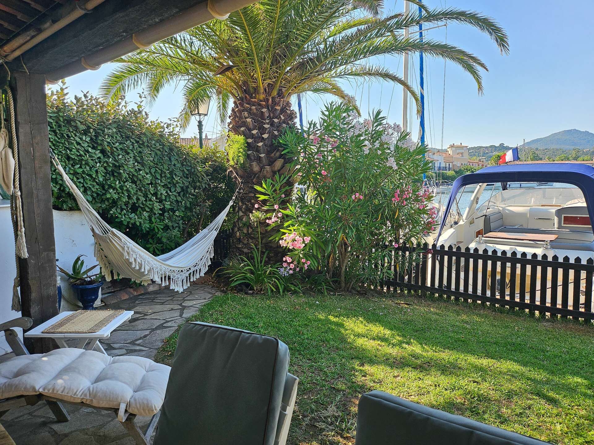 Eine Terrasse mit Sitzgelegenheit im Freien, einer Hängematte und Blick auf einen Bootssteg.