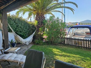 Eine Terrasse mit Sitzgelegenheit im Freien, einer Hängematte und Blick auf einen Bootssteg.