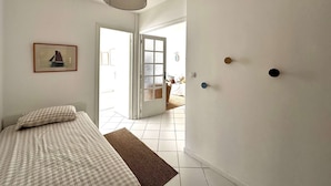 Une chambre à coucher avec un lit, une lampe suspendue, un tableau encadré et une porte donnant sur un balcon.
