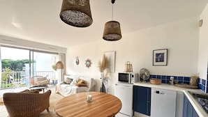 Une cuisine moderne avec un coin repas, des meubles blancs, un four à micro-ondes et un lave-vaisselle.