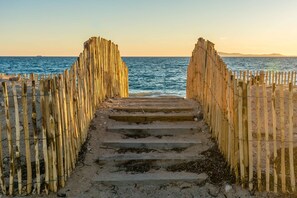 Staircase leads to a serene beach, flanked by bamboo fences.