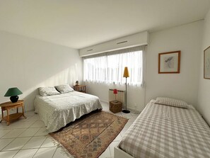 Cozy retreat with a large bed, a single bed, and a floor lamp.