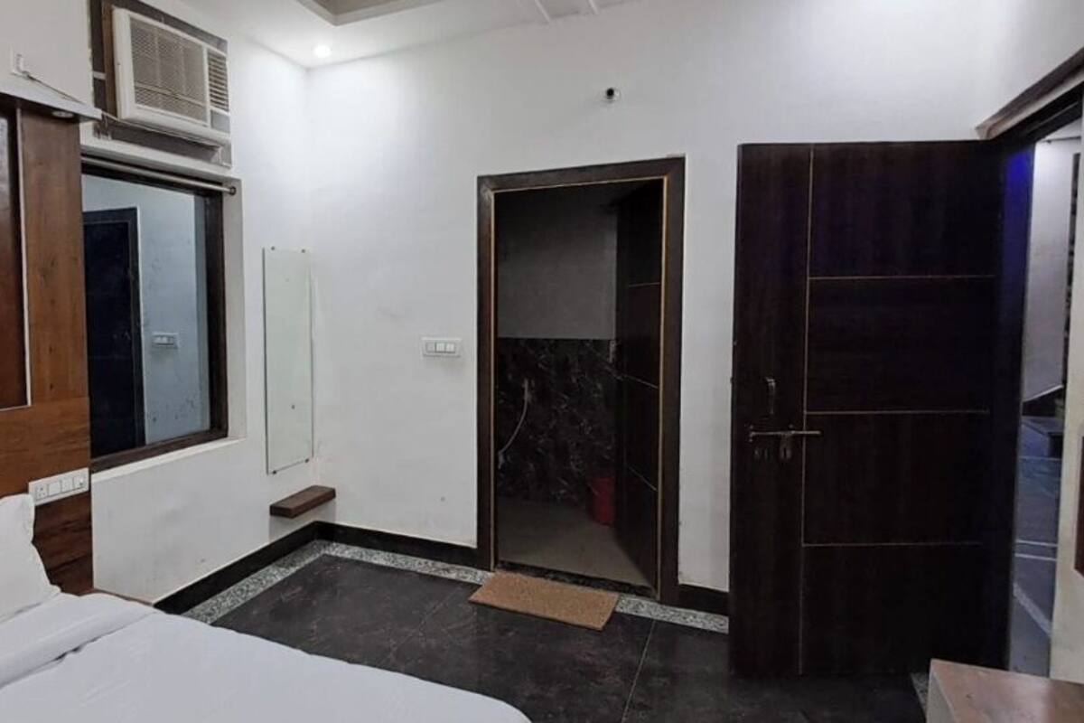 Una habitación de hotel con cama, armario, espejo y puerta.