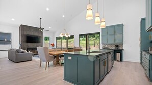 Una cocina moderna con una isla central, armarios color turquesa e iluminación colgante.